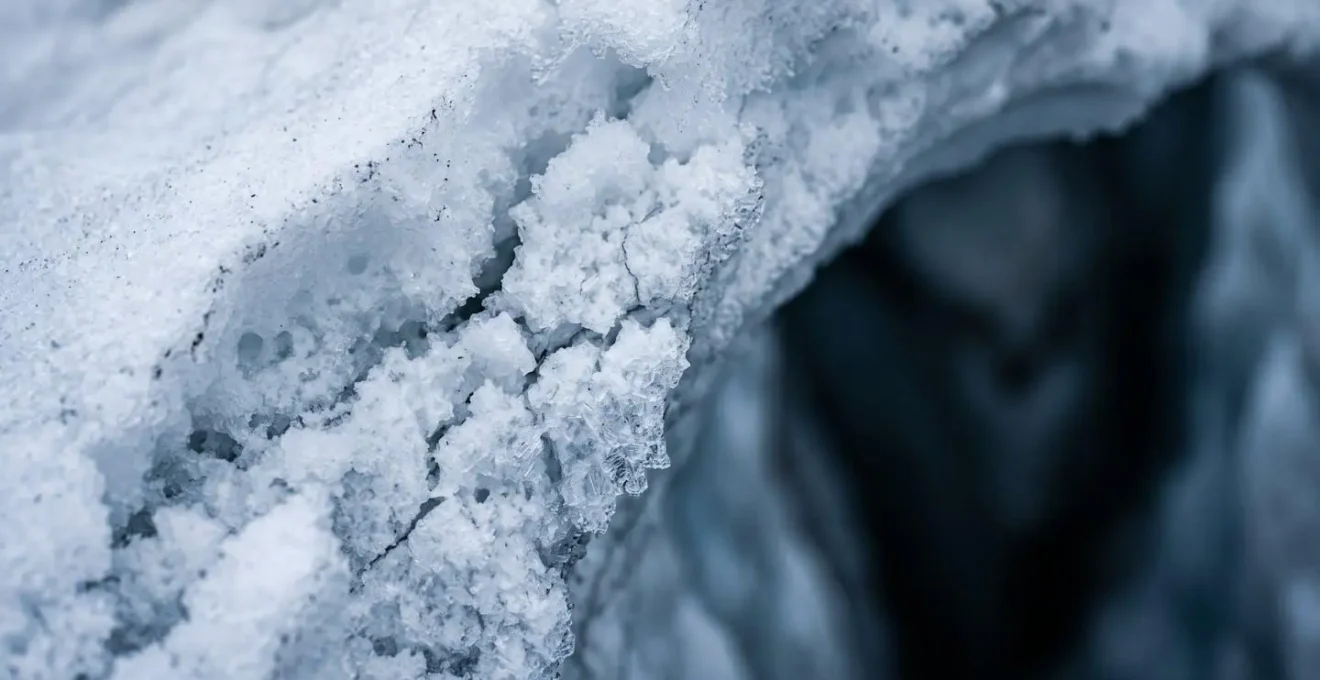 Vista macro di un ponte di neve sopra un crepaccio con evidenti segni di cedimento strutturale