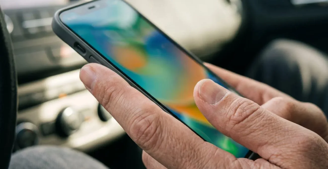 Dettaglio macro di una mano che tiene uno smartphone con schermo sfocato mostrando mappe