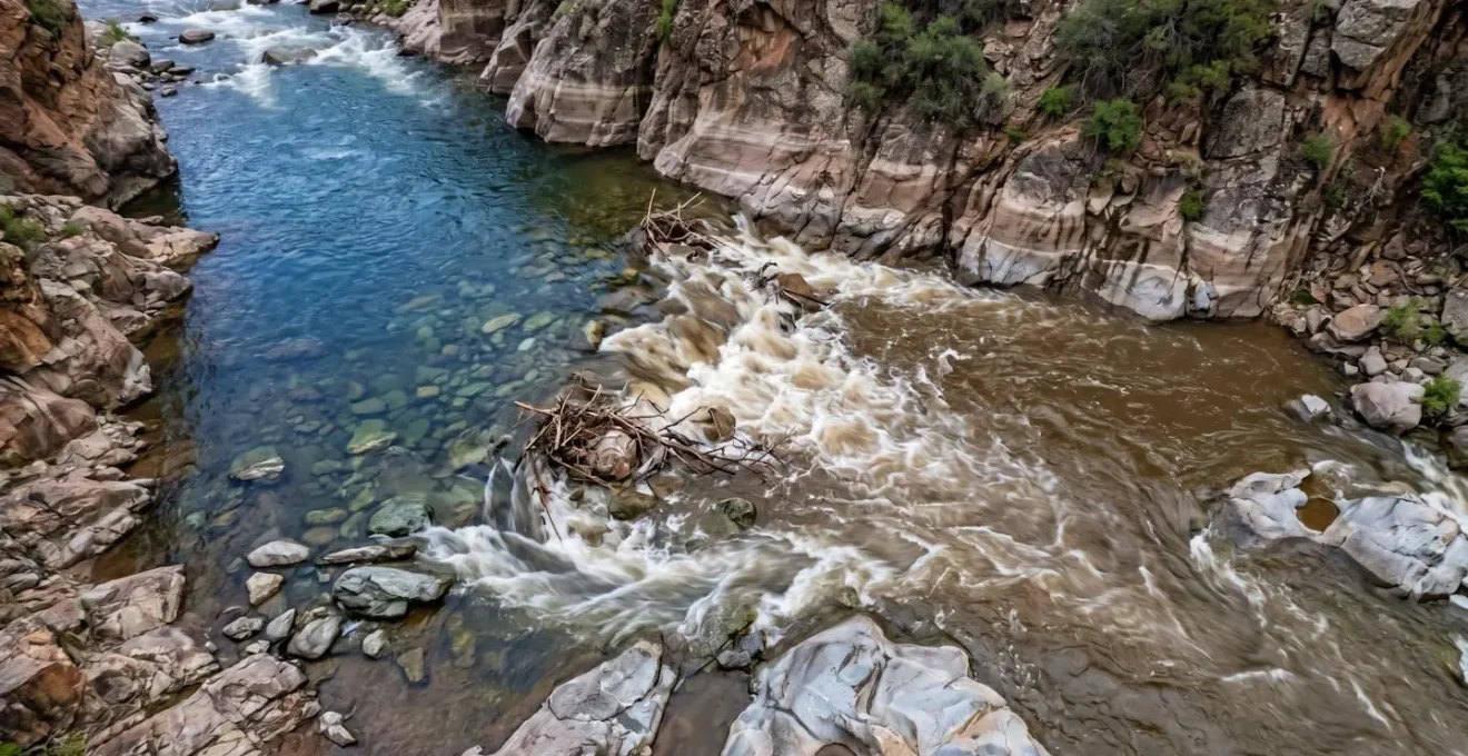 Vista dall'alto di un torrente di montagna con diversi indicatori visivi della portata dell'acqua